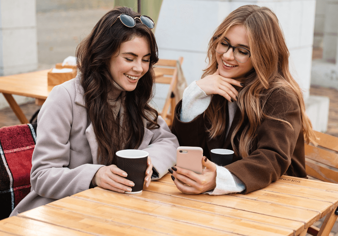 Cheerful Young Women Sitting At The Cafe